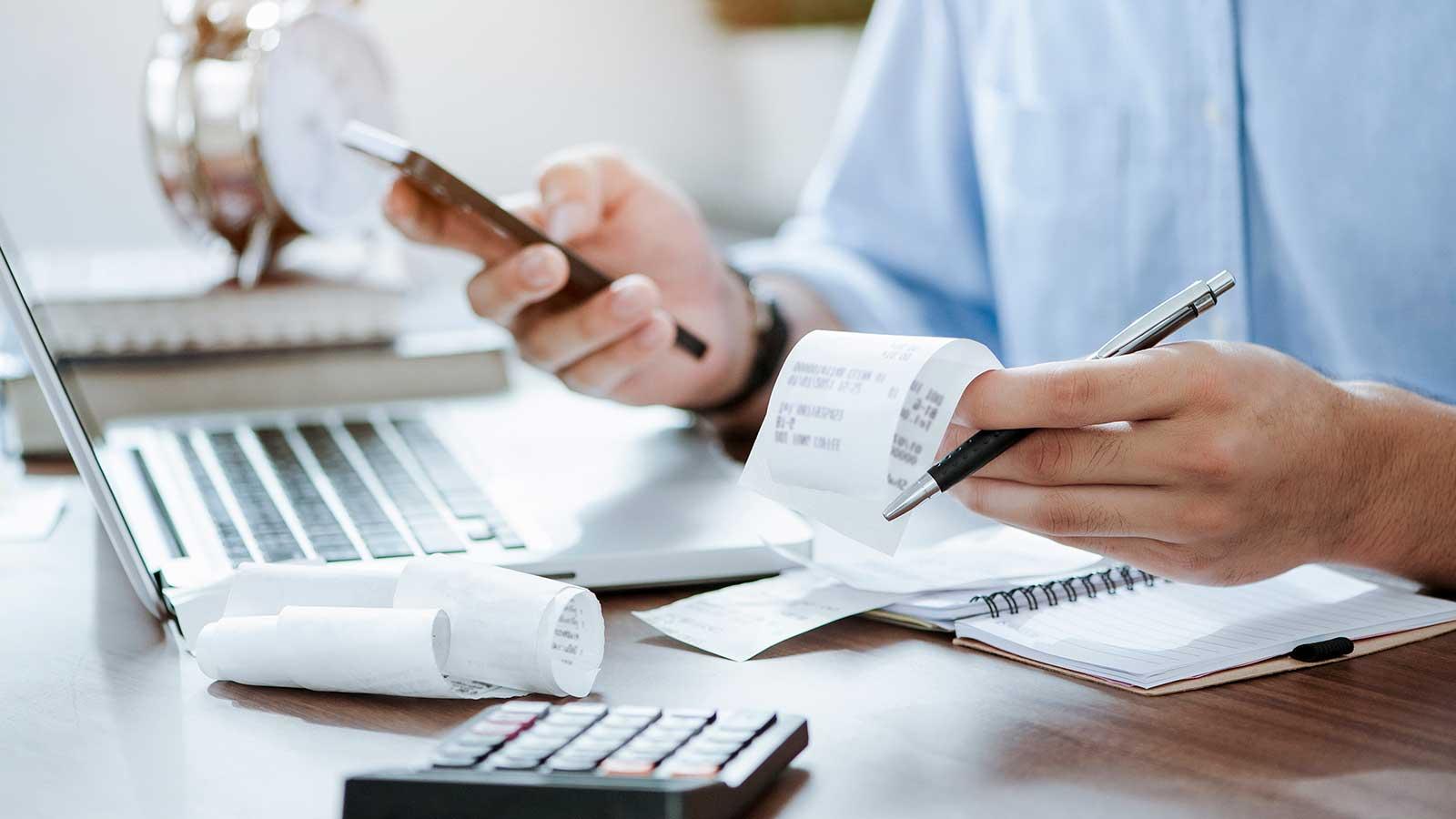 person with receipts and calculator representing financial information analytics program at Clarkson university