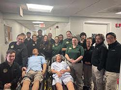 A group of EMS students poses with two EMS mannequins on stretchers